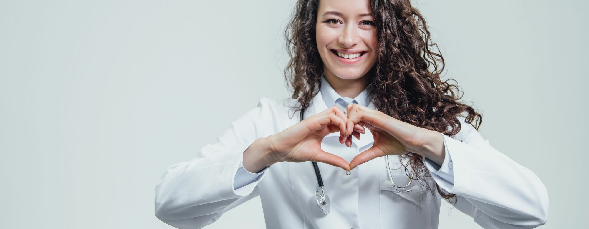 Eine junge Ärztin formt mit ihren Händen ein Herz